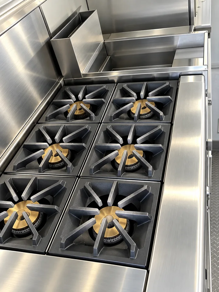 Commercial six-burner range inside a 24 ft mobile kitchen